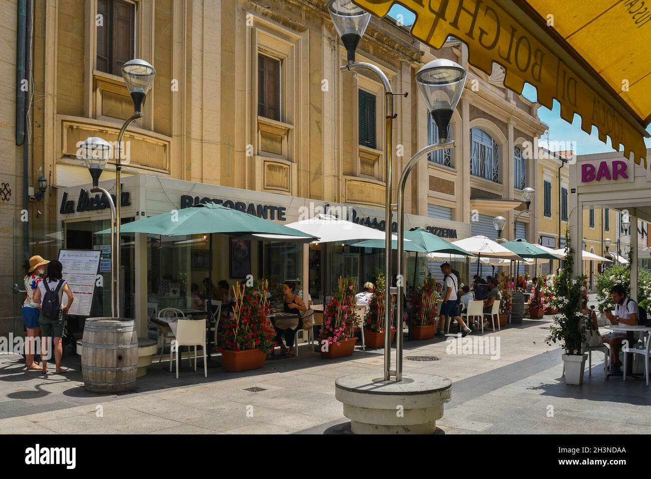 Straßenansicht des Fischerdorfes an der toskanischen Küste mit Menschen in Cafés und Restaurants im Freien im Sommer, San Vincenzo, Livorno, Toskana, Italien Stockfoto