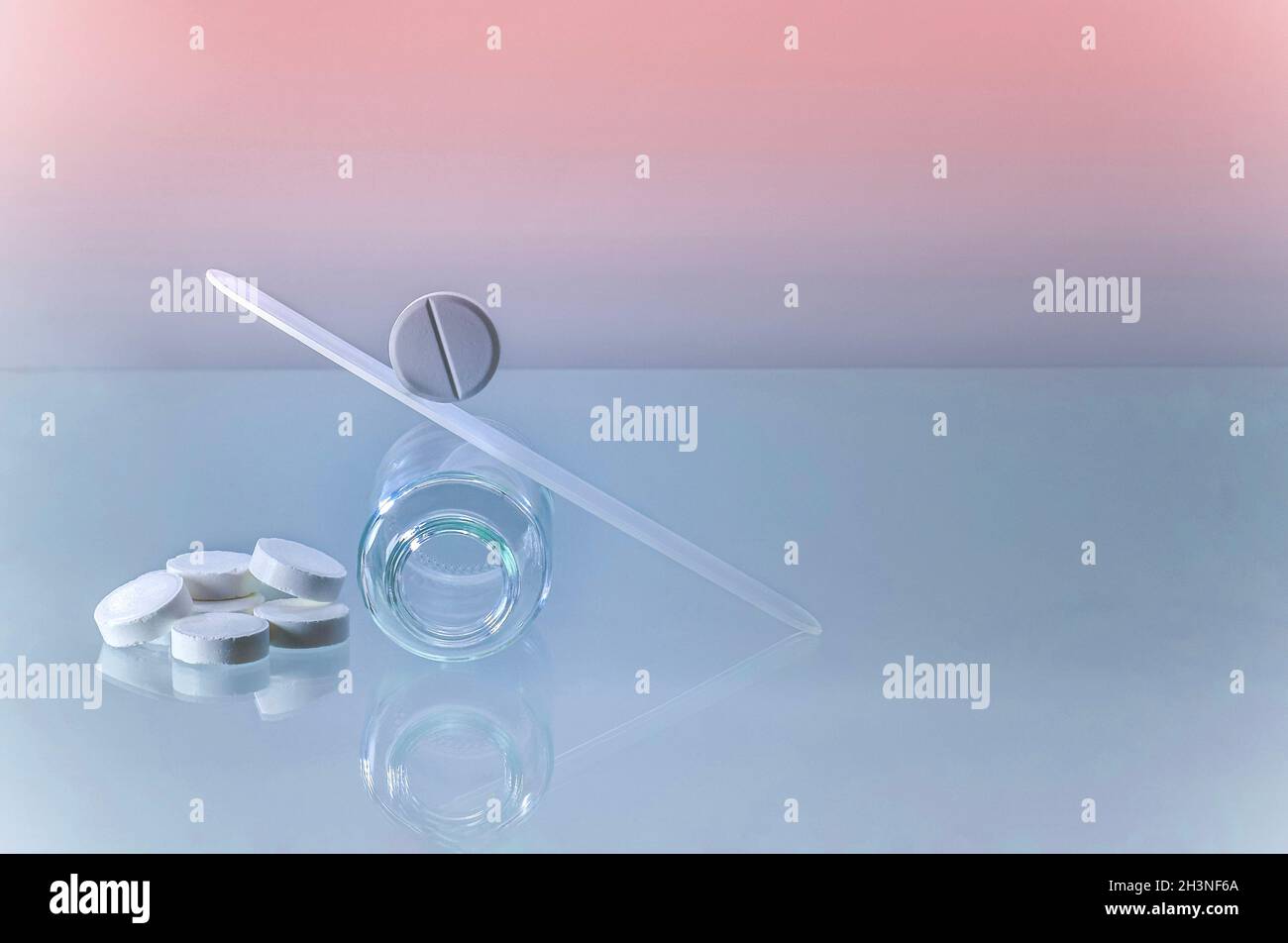 Die Pille rollt eine Schminkrutsche mit Schaukeln auf einem leeren Glas auf den Kopf. Stockfoto