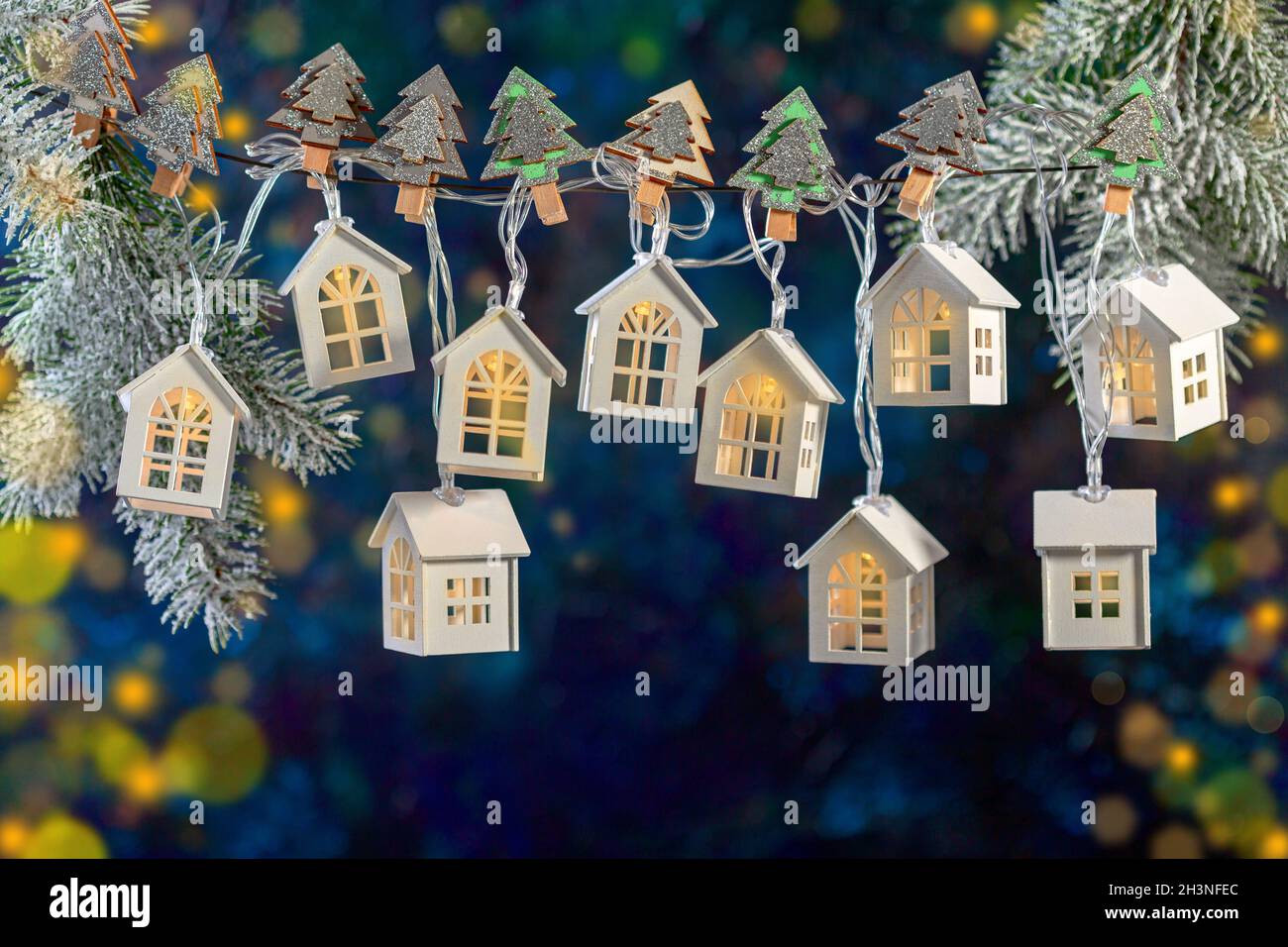 Weihnachtsgirlande aus Lichtern in Form von weißen Häusern. Stockfoto