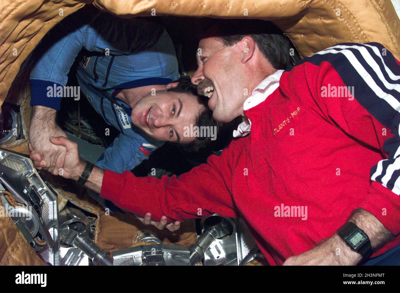 ERDORBIT - 01. Juli 1995 - STS-71-Missionskommandant Robert Hoot Gibson (Vordergrund) bietet seinem russischen Amtskollegen M ein breites Lächeln und einen Handschlag Stockfoto