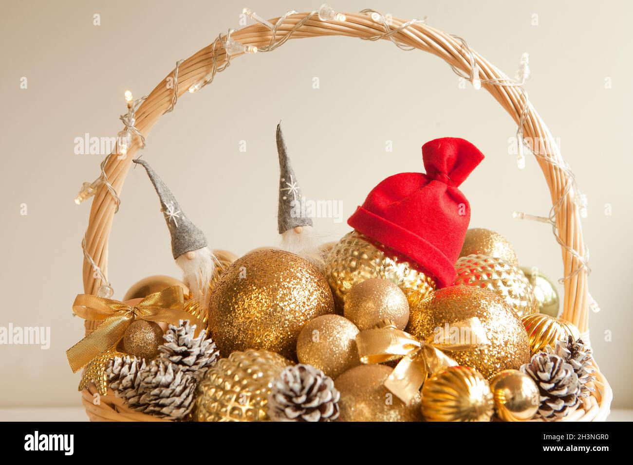 goldene Kugeln am riesigen Korbkorb mit rotem weihnachtsmann Hut. Dekoration für Weihnachtstanne oder Apartmen Stockfoto