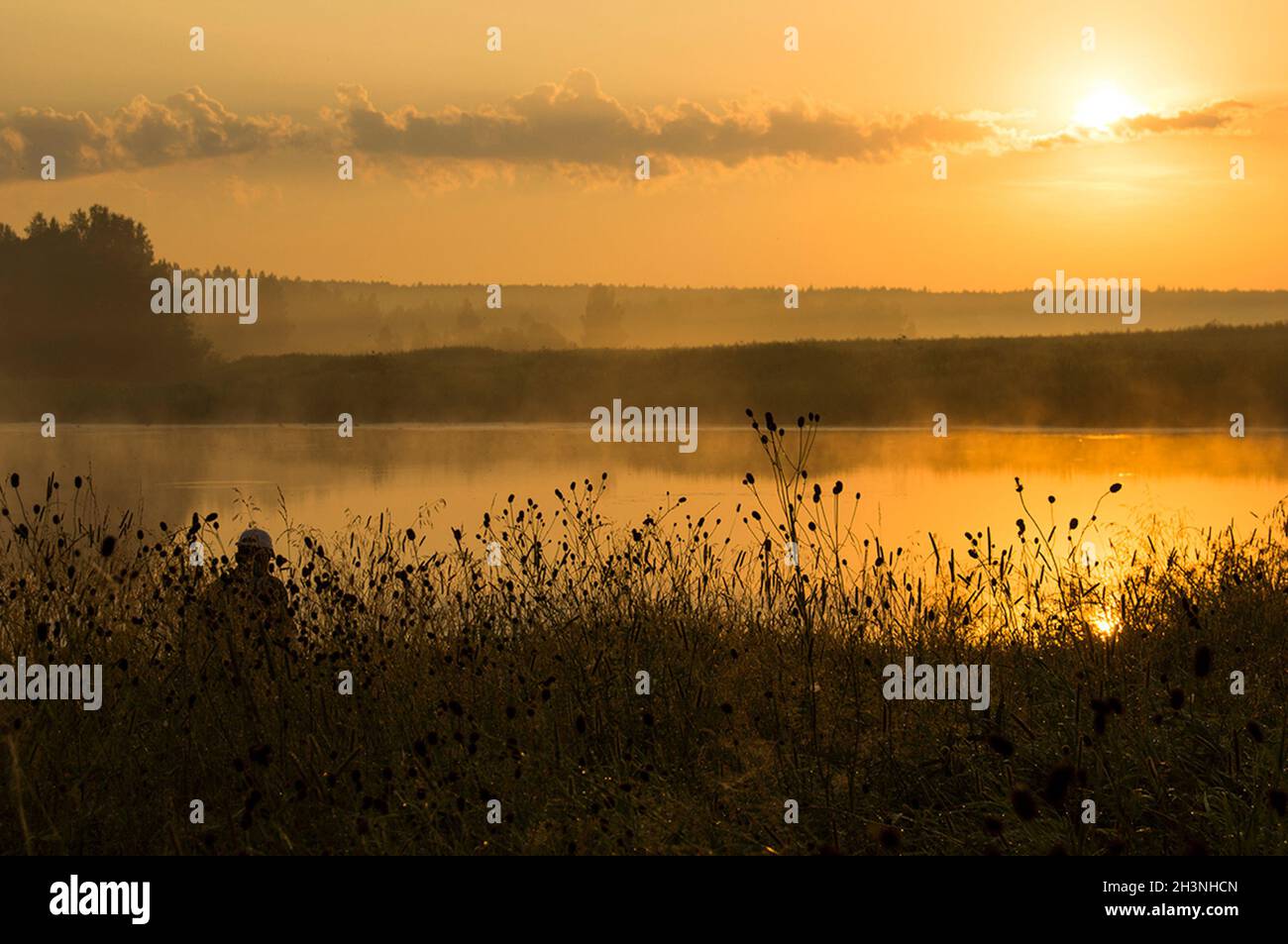 Ein Fischer bei Sonnenuntergang am Teich fängt Fische. Stockfoto
