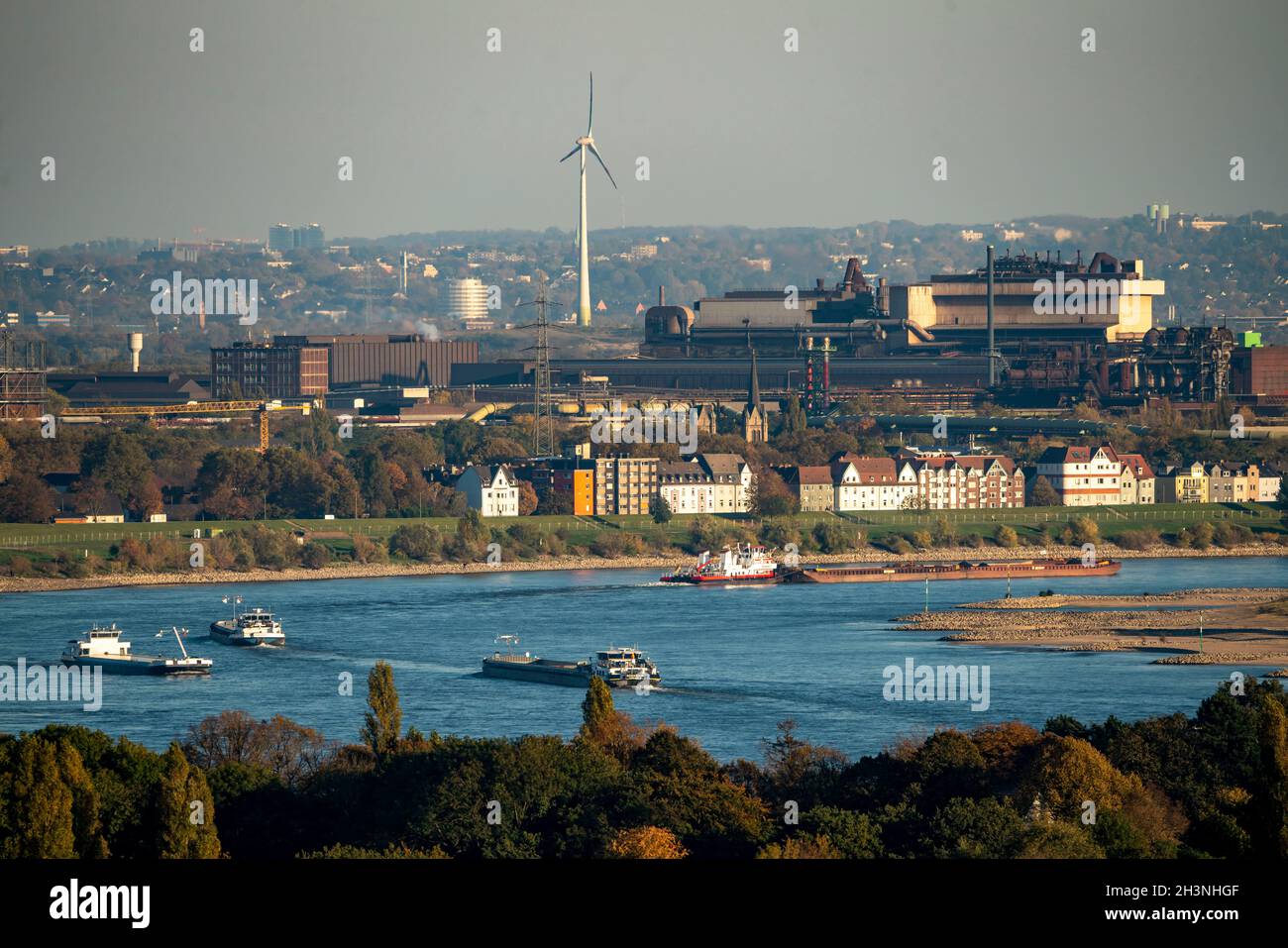 Frachtschiffe auf dem Rhein bei Duisburg, Häuser auf der Deichstraße, industrielle Kulisse des Stahldrahtwerks ArcelorMittal Hochfeld GmbH, NRW Stockfoto