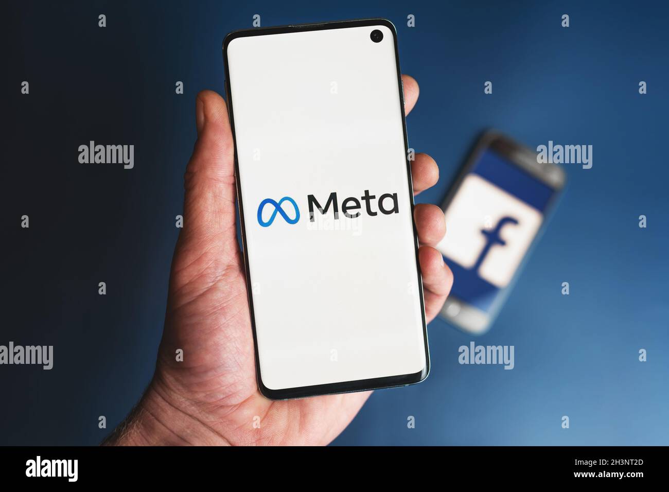 DAS META-Logo auf dem Smartphone wird mit dem Facebook-Symbol in der Hand vor dem Telefon gehalten. Facebook ändert den Firmennamen in Meta und konzentriert sich bei der Neumarkation auf Metaverse. Swansea, Großbritannien - 30. Oktober 2021. Stockfoto