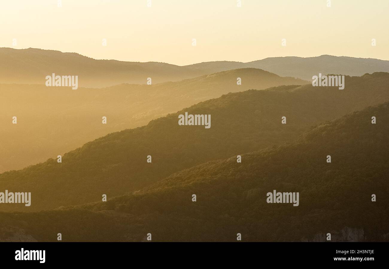 Morgendämmerung in den Bergen der Krim. Licht Dunst über den Bergen und Strahlen der Sonne durch die Wolken. Stockfoto