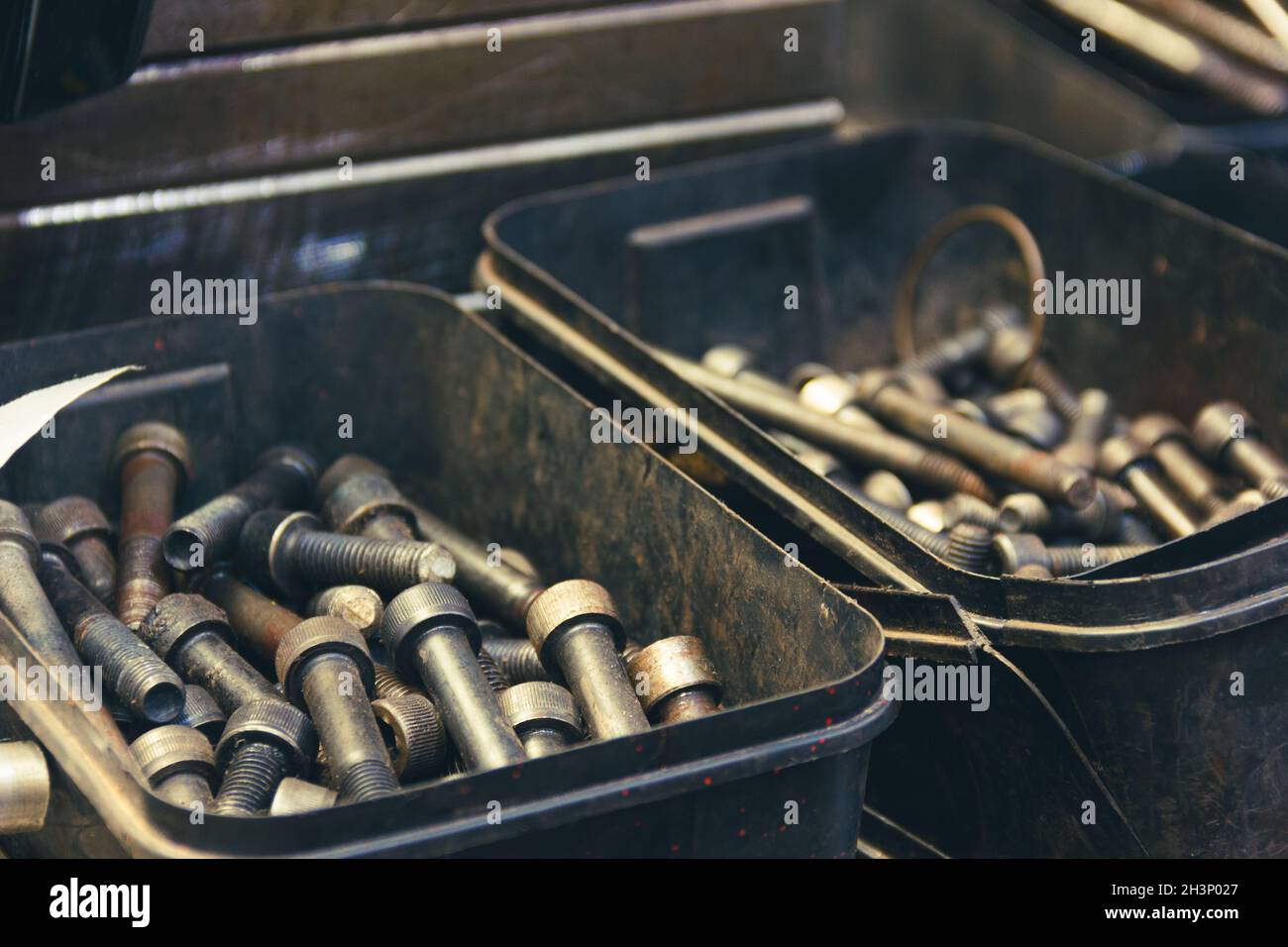 Sätze von dicken Stahlschrauben in Kunststoffkästen. Industrielles Fabrikmaterial, Vintage-Effekt Stockfoto