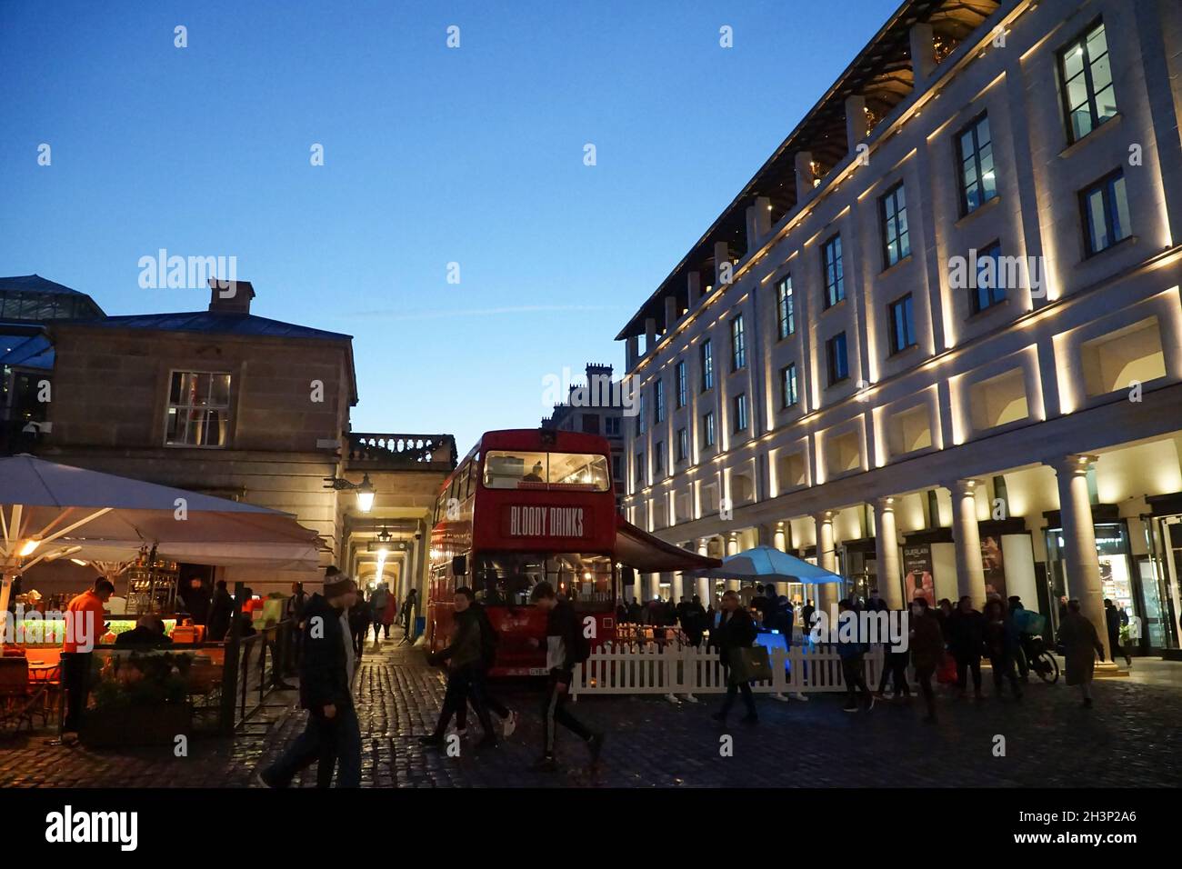 London, Großbritannien, 29. Oktober 2021: Während die Abenddämmerung in Covent Garden und den umliegenden gepflasterten Straßen einbricht, genießen Touristen und Einkäufer einen trockenen Zauber zwischen Regenschauern. Diners und Trinker in Bars, Pubs oder Restaurants haben oft die Wahl, drinnen oder draußen zu sitzen. Werbekampagnen, die Menschen zu einem Besuch in London ermutigen, scheinen viele halbzeitige Familienbesuche angelockt zu haben, und London hat derzeit eine geringere Rate an kovidierten Infektionen als einige andere Gebiete des Landes. Im zentralen Marktbereich sind bereits Weihnachtsdekorationen zu sehen. Anna Watson/Alamy Live News Stockfoto
