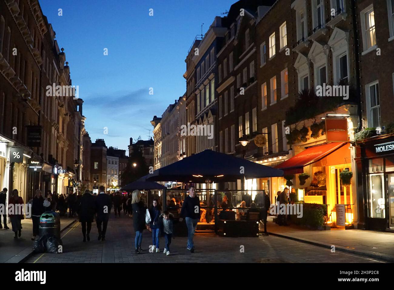 London, Großbritannien, 29. Oktober 2021: Während die Abenddämmerung in Covent Garden und den umliegenden gepflasterten Straßen einbricht, genießen Touristen und Einkäufer einen trockenen Zauber zwischen Regenschauern. Diners und Trinker in Bars, Pubs oder Restaurants haben oft die Wahl, drinnen oder draußen zu sitzen. Werbekampagnen, die Menschen zu einem Besuch in London ermutigen, scheinen viele halbzeitige Familienbesuche angelockt zu haben, und London hat derzeit eine geringere Rate an kovidierten Infektionen als einige andere Gebiete des Landes. Im zentralen Marktbereich sind bereits Weihnachtsdekorationen zu sehen. Anna Watson/Alamy Live News Stockfoto