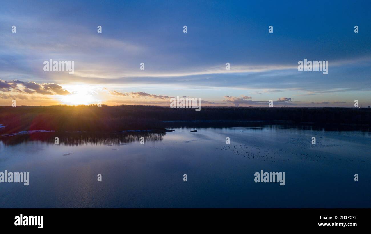 Luftaufnahme eines schönen und dramatischen Sonnenuntergangs über einem Waldsee, der sich im Wasser spiegelt, Landschafts-Drohne aufgenommen Stockfoto
