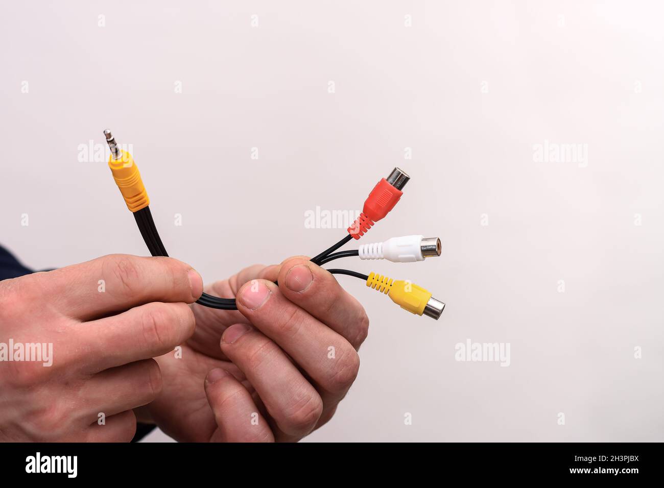 Audio-Video-Kabel RCA-Buchse in den Händen eines Mannes auf weißem Hintergrund. Stockfoto