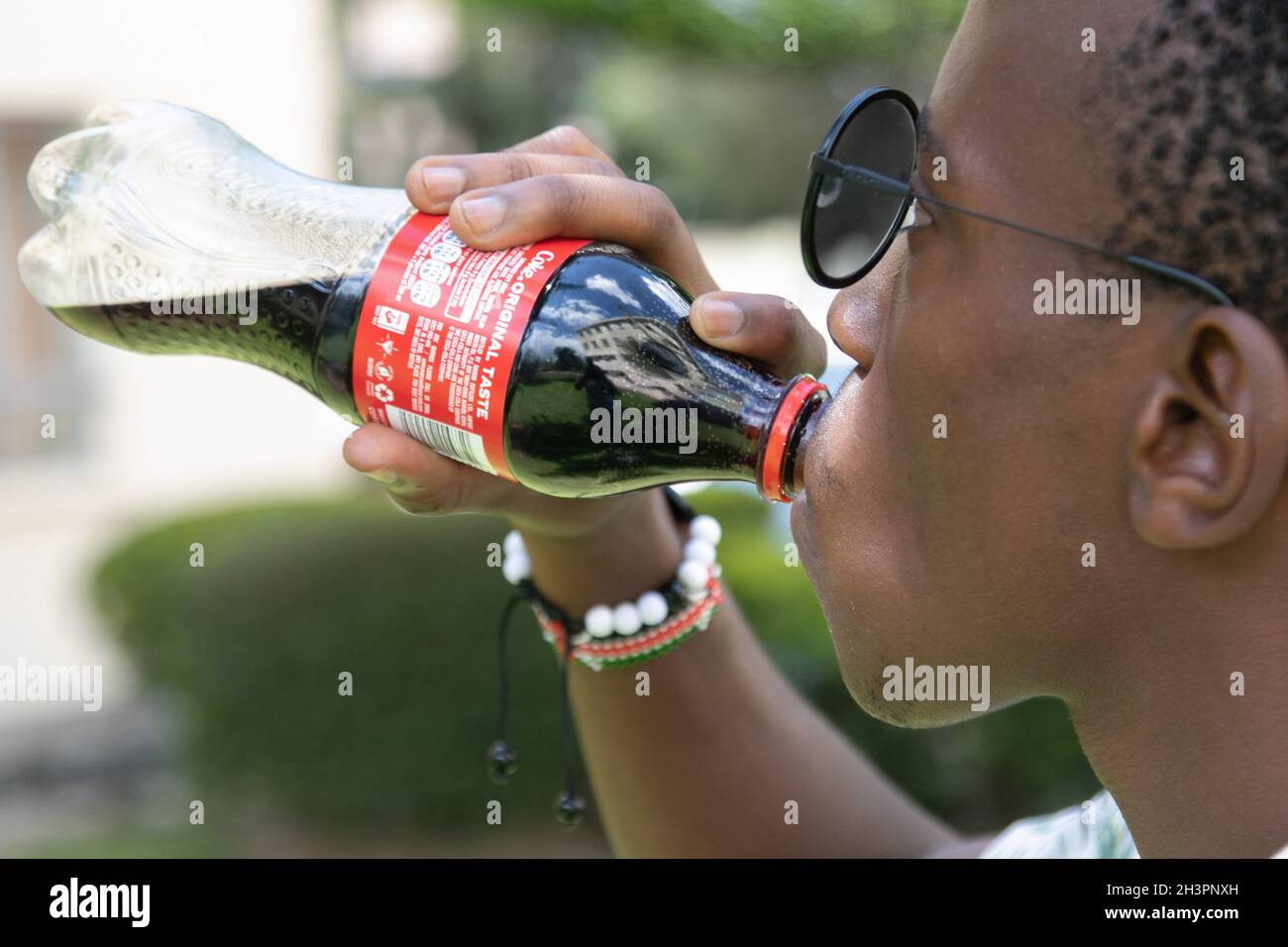 Auf dieser Fototafel sah ein Mann Coca-Cola trinken. Durchschnittlich 38 % der Kunststoffabfälle, die in der Nähe des Lake Nakuru National Park, einem UNESCO-Weltkulturerbe, gesammelt werden, stammen von US-amerikanischen Unternehmen, deren Coca-Cola 44 % der von Unwaste.io, einem britischen Sozialunternehmen, gesammelten und geprüften Flaschen ausmacht. Andere internationale Audits haben Coca-Cola als den größten Beitrag zu Kunststoffabfällen angeführt. Umweltlobby-Gruppen fordern Unternehmen auf, Verantwortung für das Ende der Lebensdauer ihrer Produkte zu übernehmen, um die Umwelt zu schützen. (Foto von James Wakibia/SOPA Images/Sipa USA) Stockfoto