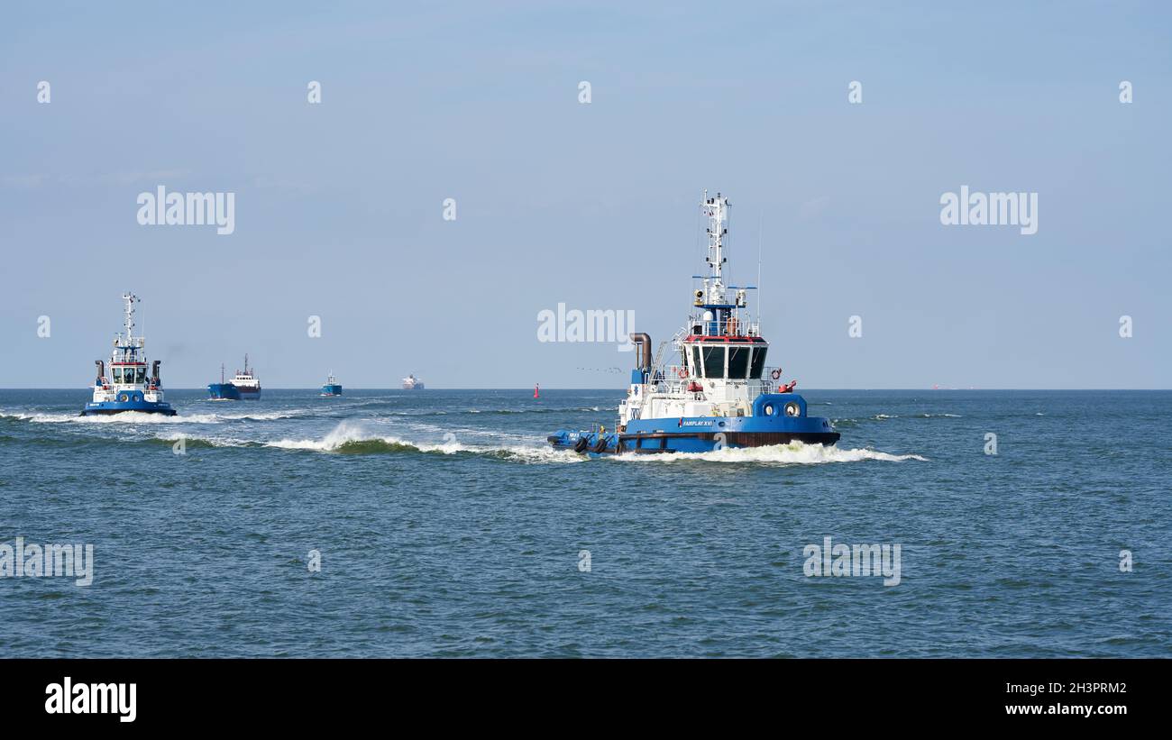Schlepper, der ein Schiff auf dem Weg zum Hafen begleitet Von Swinoujscie an der polnischen Küste der Ostsee Stockfoto
