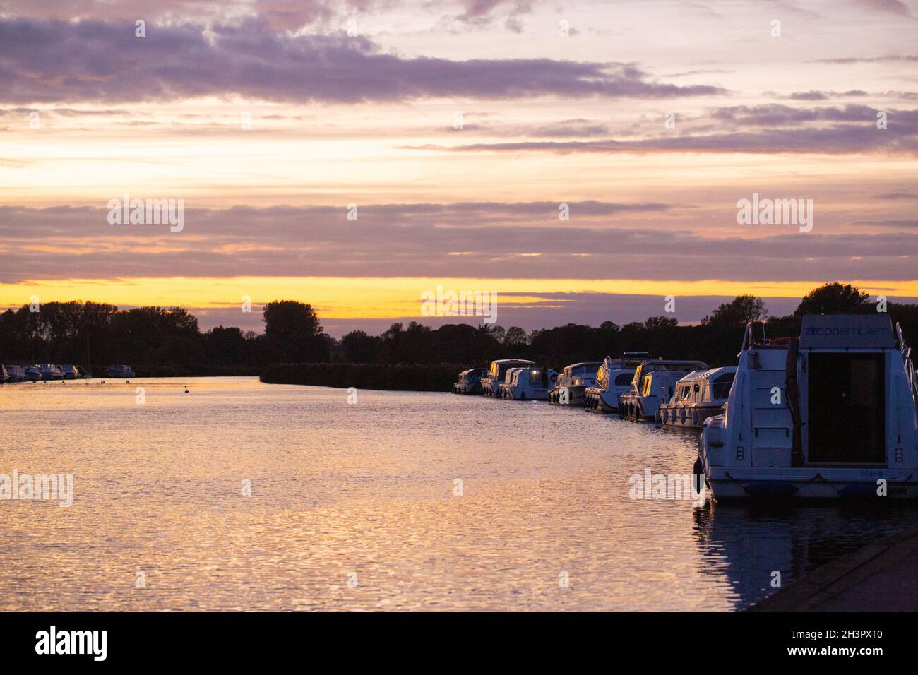Abenduntergang. Bunte Wolkenschichten spiegeln sich auf der Oberfläche von River Bure, Acle Bridge, Broadland, Norfolk, National Park. Urlaub, Urlaub, Cruis Stockfoto