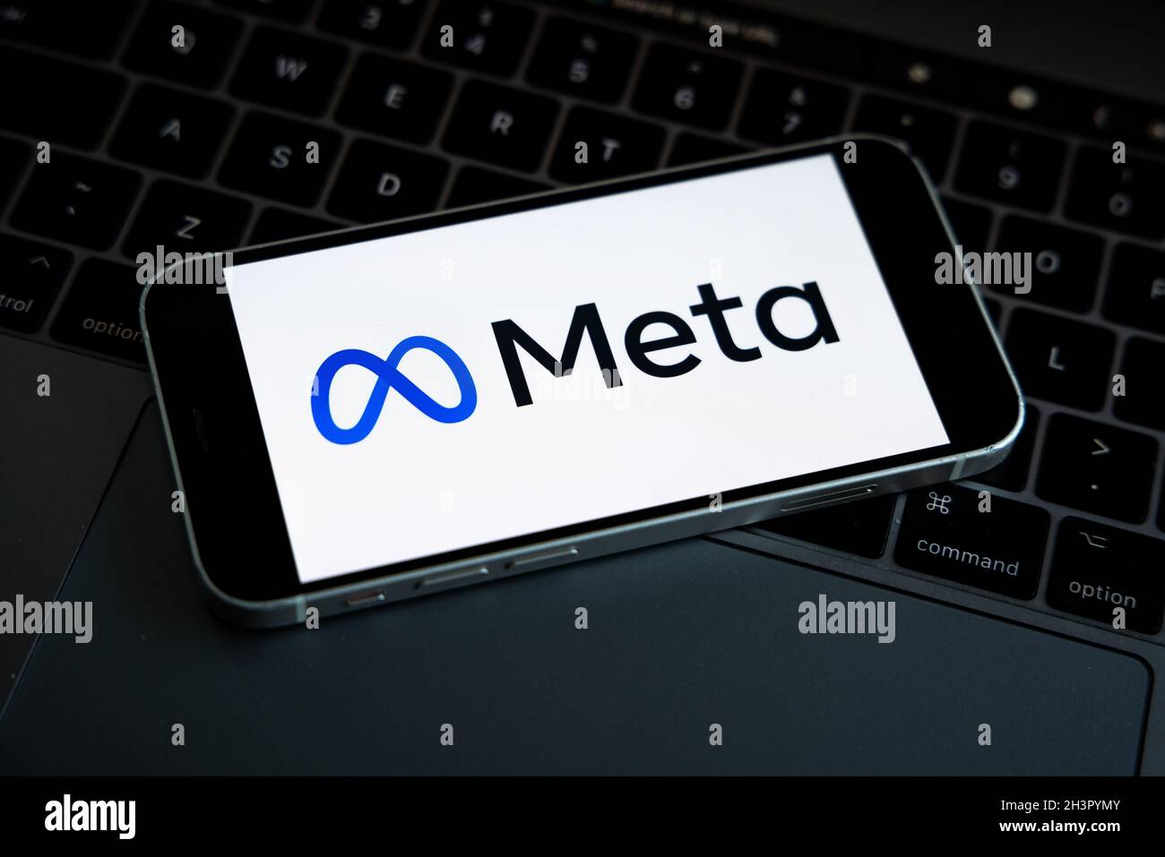 META-Firmenlogo auf dem Smartphone in der Hand mit Facebook-Logo auf dem Hintergrundbildschirm gesehen. Neues Facebook-Firmenlogo für METAVERSE. Stockfoto