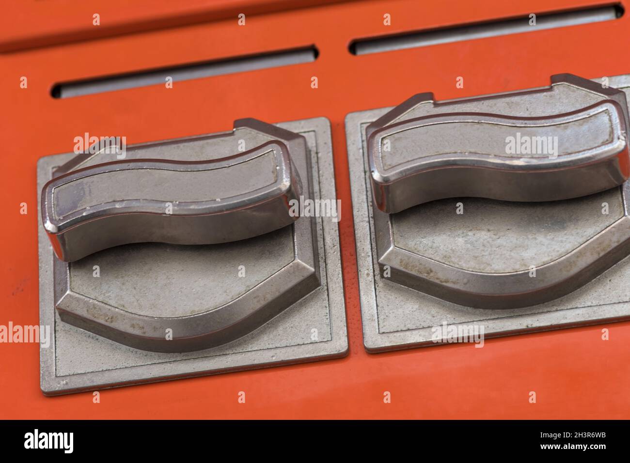 Nahaufnahme der rotierenden Chromräder eines orangefarbenen Kaugummi-Automaten Stockfoto