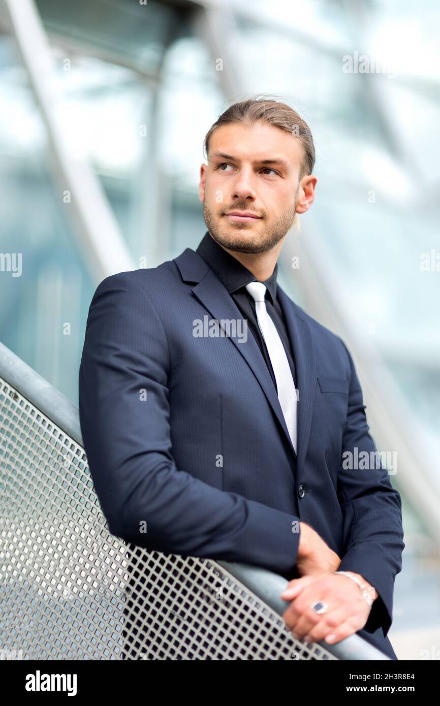 Hübscher, stilvoller junger Geschäftsmann, der im Freien ein Porträt posiert Stockfoto