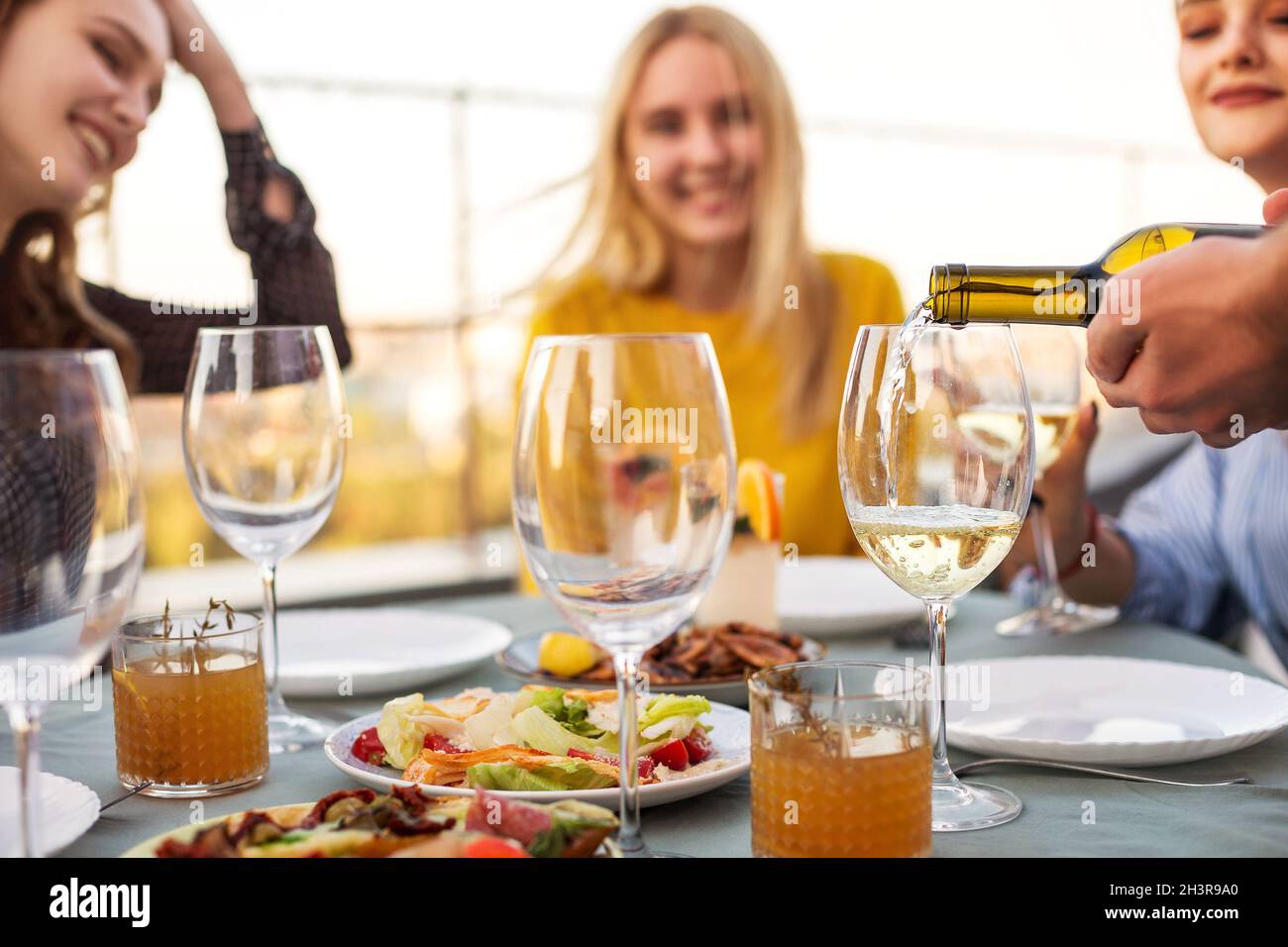 Glückliche Freunde warten darauf, dass der Kellner Wein gießt Stockfoto