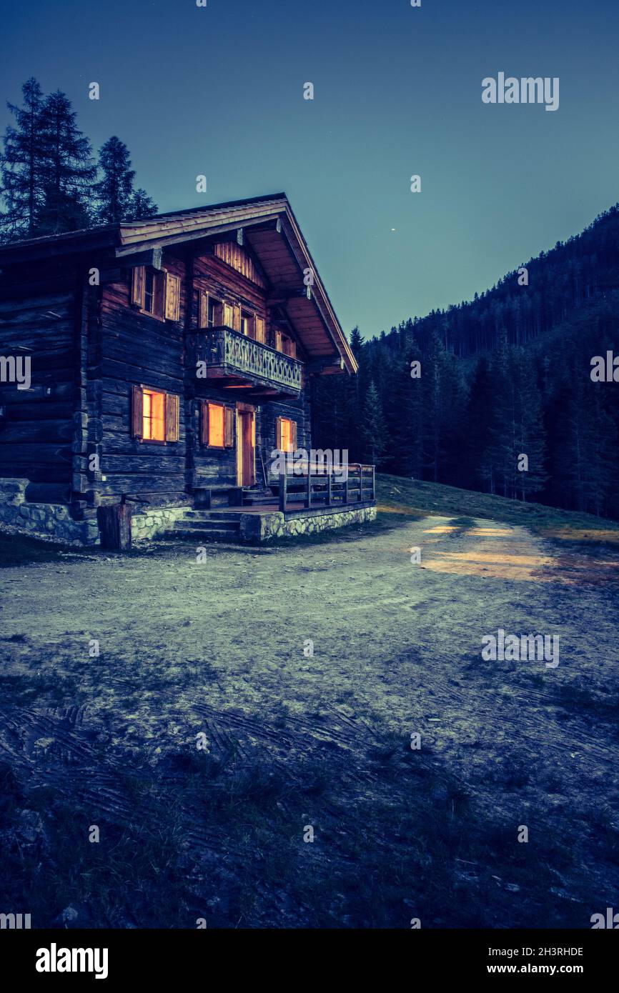 Urlaub in den alpen: Urige Holzbauernhütte in der Nacht. Stockfoto