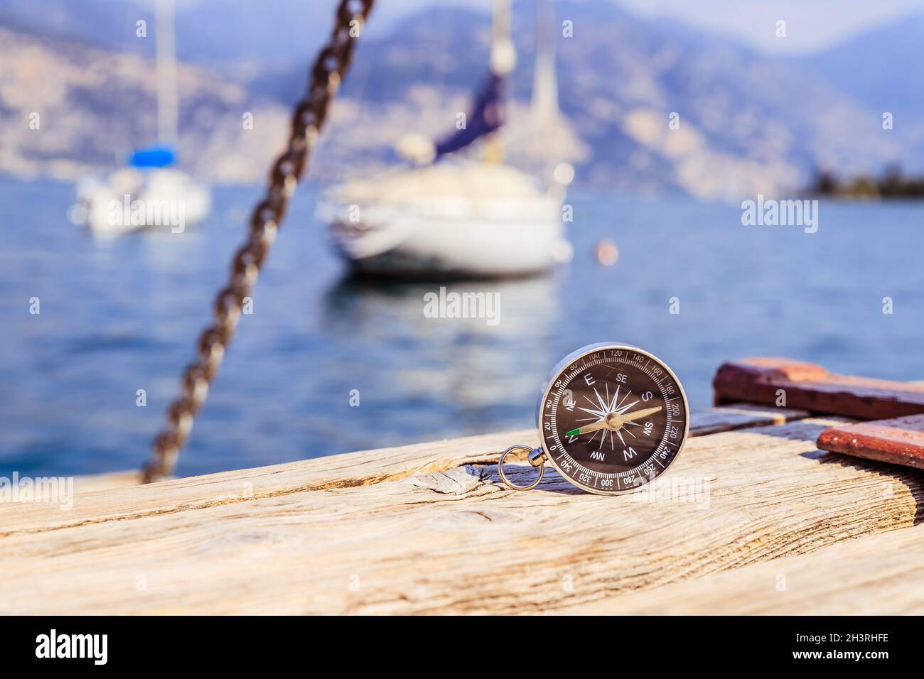 Segeln: Seekompass auf hölzernen Dock Pier. Segelboote im Hintergrund. Stockfoto