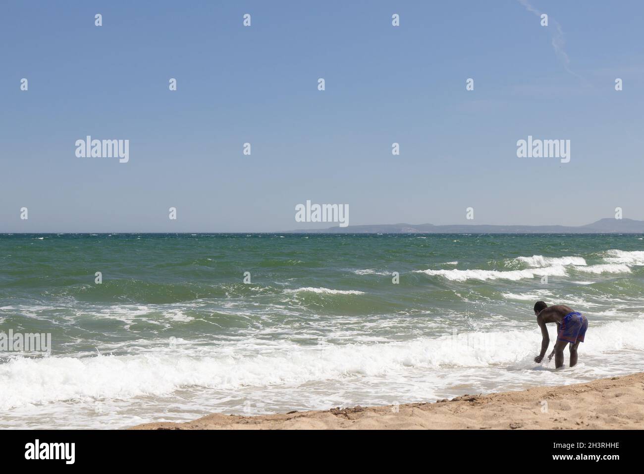 Ozean und schwarzer Mann, der am Meeresstrand spielt. Afrikanischer Mann, der neben dem Meer steht. Mann, der während der Sommerferien am tropischen Strand einer exotischen Insel spielt. Co Stockfoto