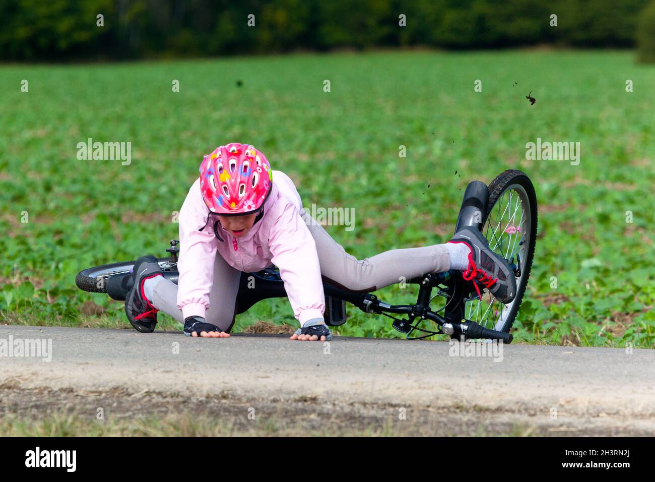 Kind fällt vom Fahrrad, Kind mit Helm, Unfall im Freien Stockfoto