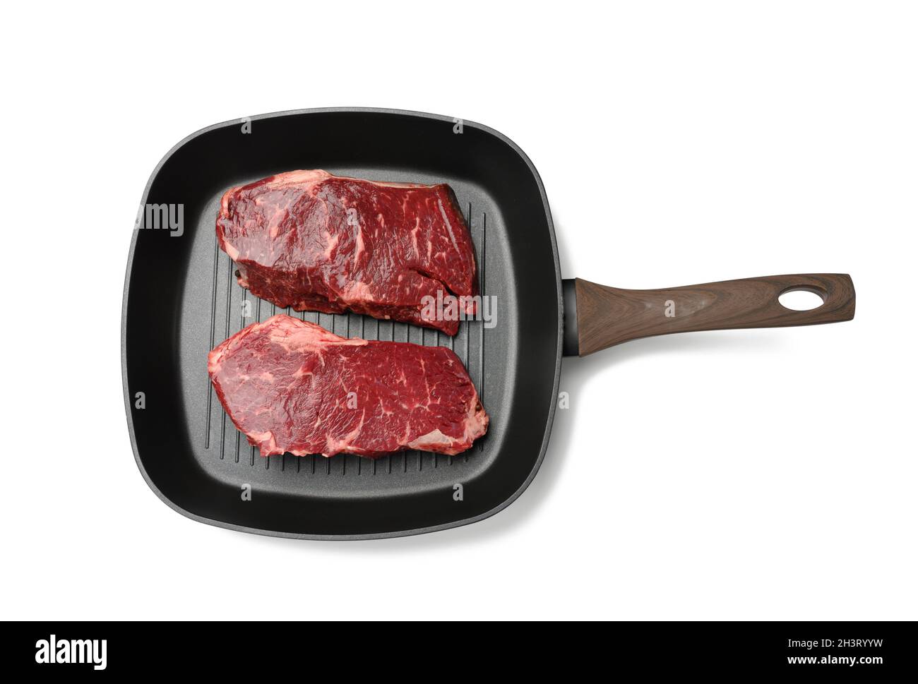 Zwei rohe Stücke Rindfleisch in einer schwarzen quadratischen Grillpfanne, Steaks isoliert auf weißem Hintergrund Stockfoto