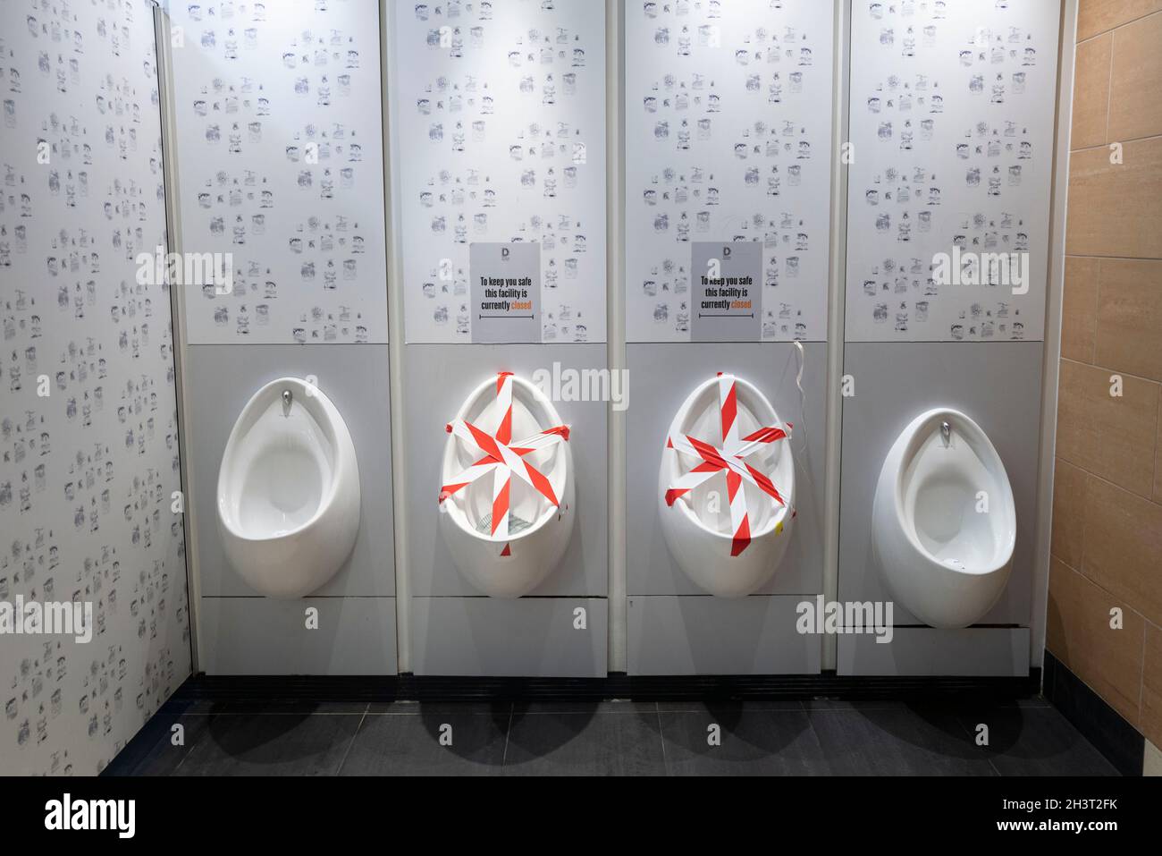 Urinale in männlichen Toiletten wurden während der Coronavirus-Pandemie abgeklebt. Stockfoto