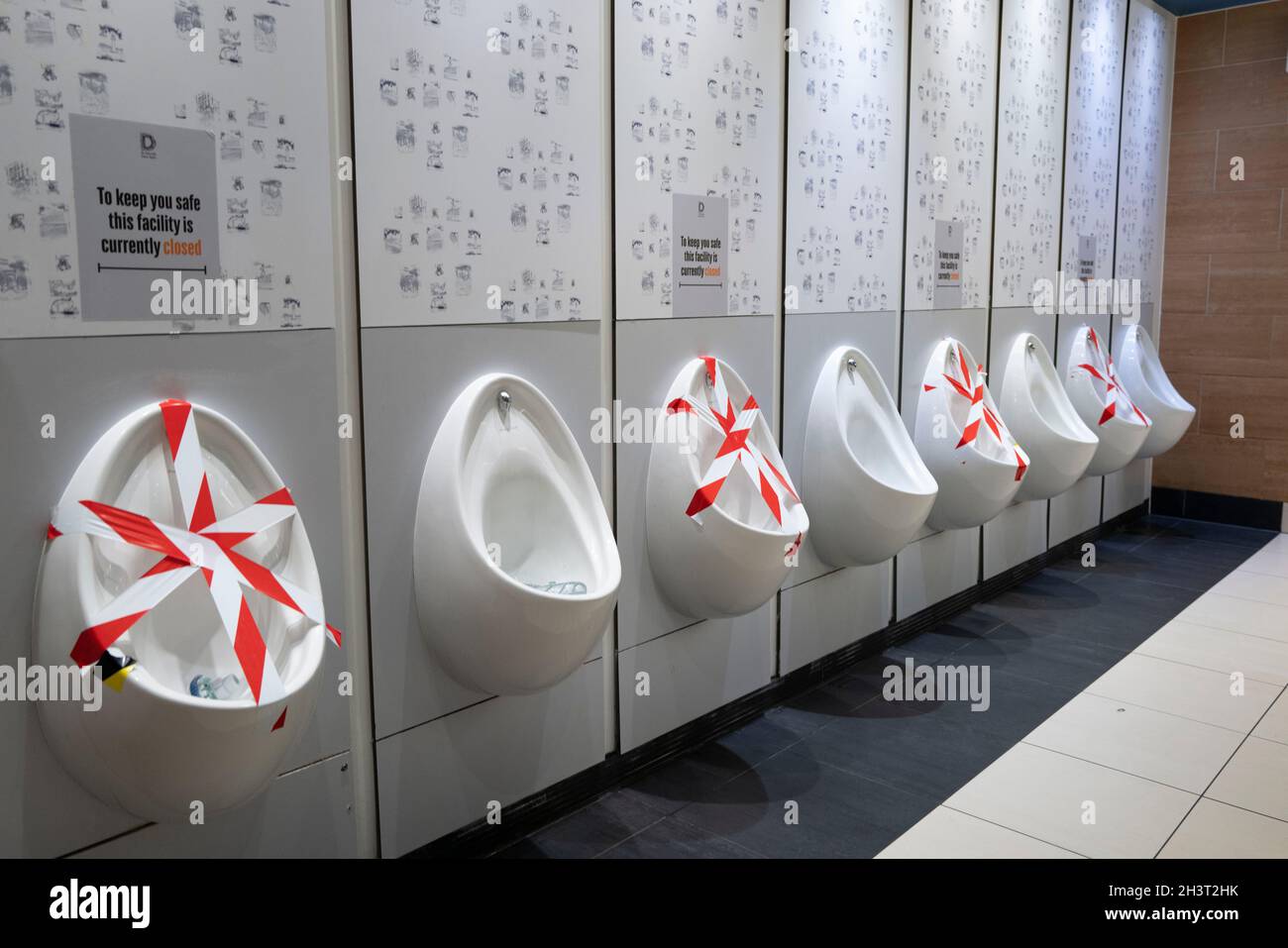 Urinale in männlichen Toiletten wurden während der Coronavirus-Pandemie abgeklebt. Stockfoto