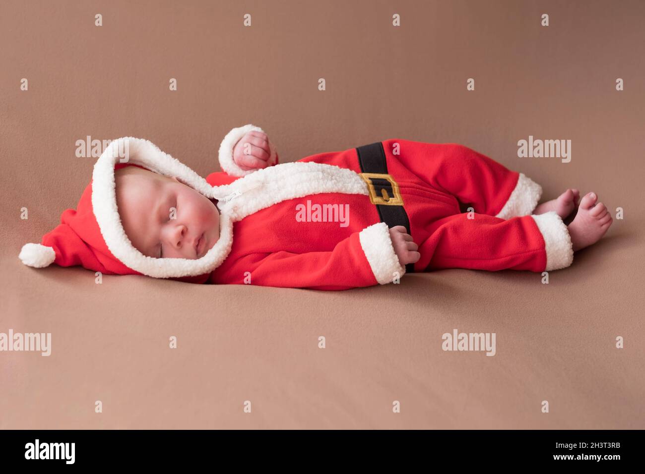 Neugeborenes Mädchen in weihnachtsmann Kostüm gähnend müde gekleidet. Stockfoto