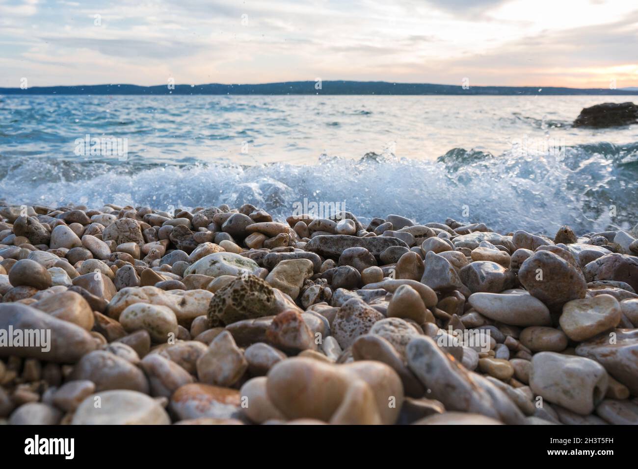 Geheimnisvoller Blick auf Steine und Kieselsteine im Wasser nach Sonnenuntergang im Sommer. Stockfoto