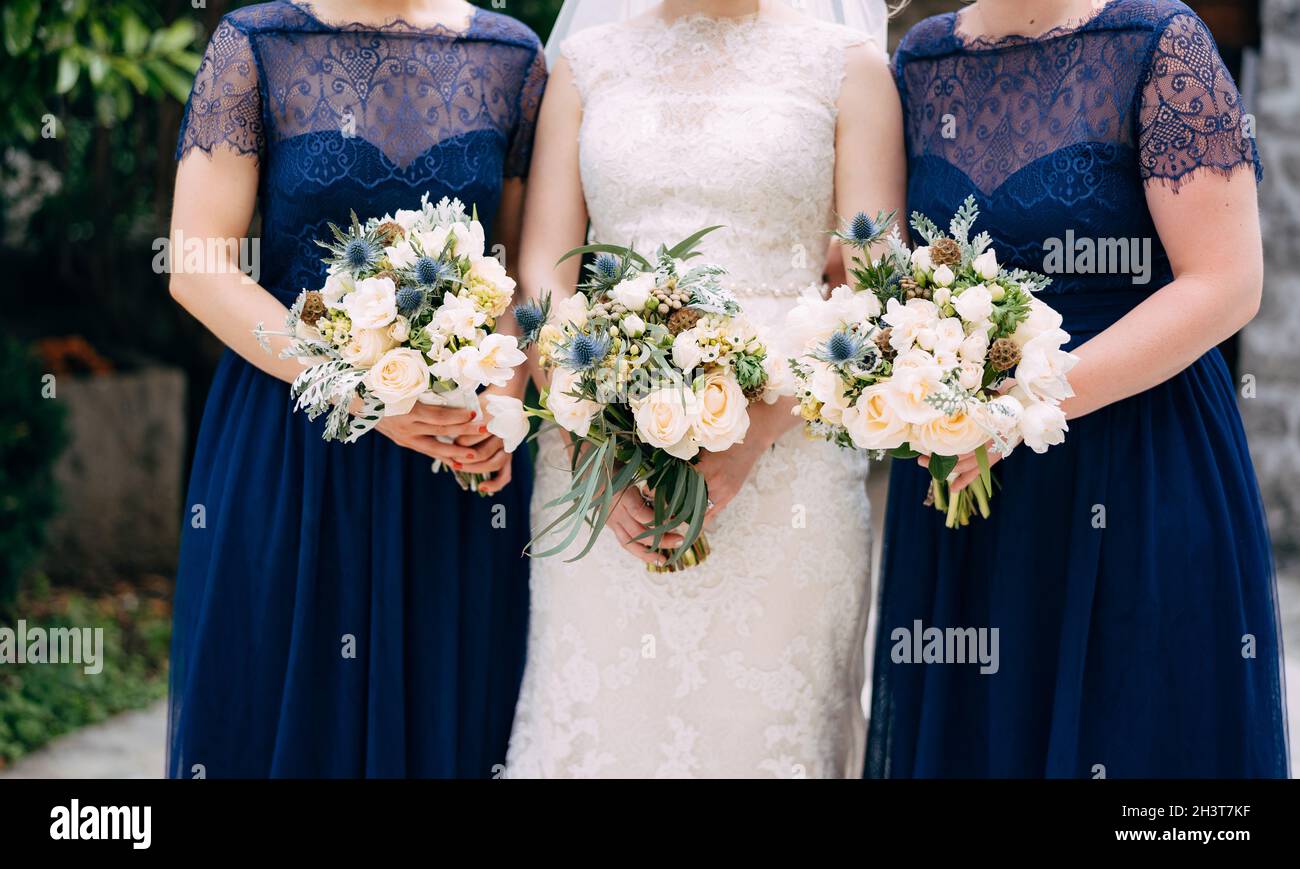 Braut und Brautjungfern in identischen blauen Kleidern stehen nebeneinander und halten Blumensträuße in den Händen, aus nächster Nähe Stockfoto