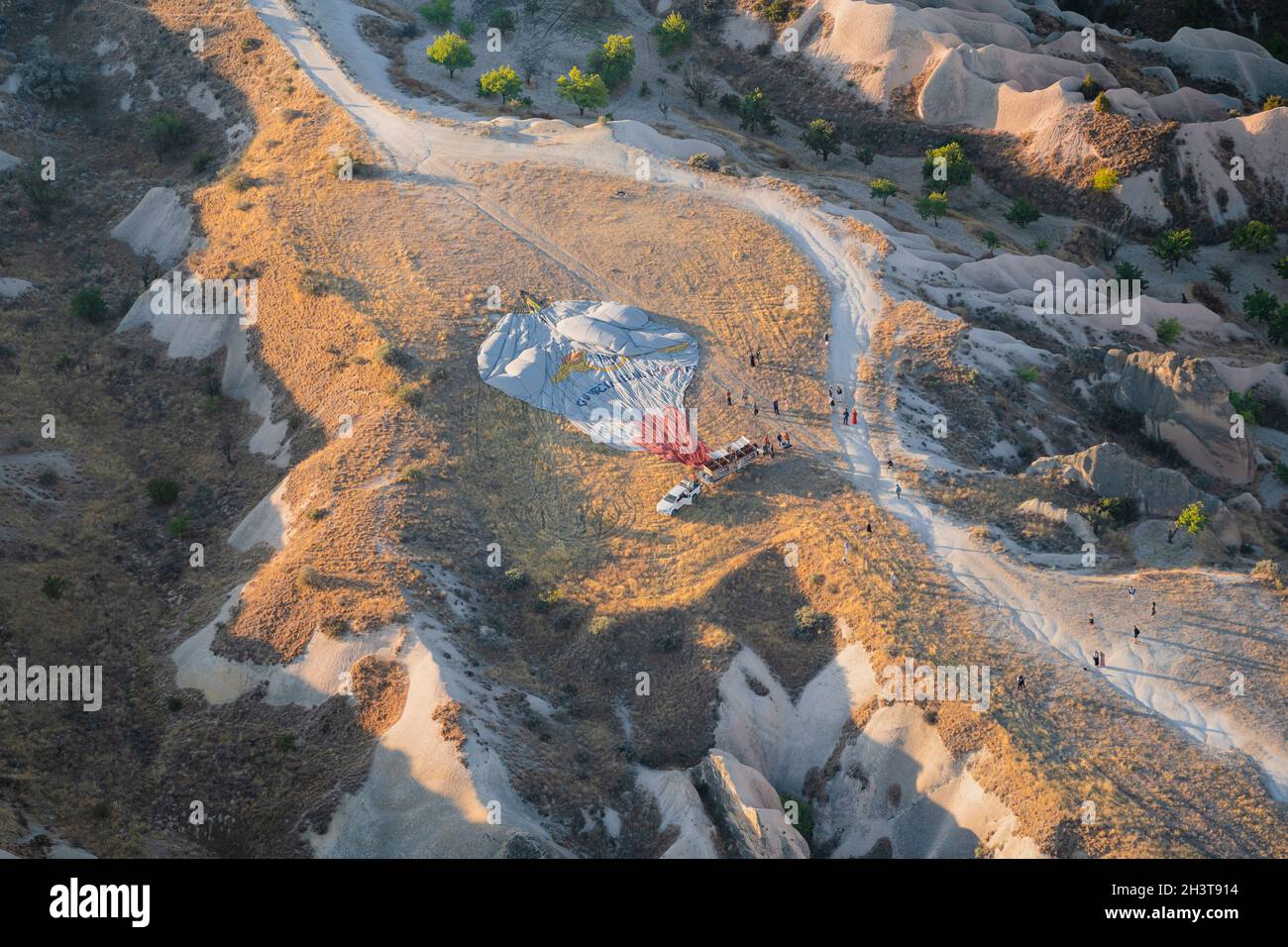 GOREME, TÜRKEI - 3. AUGUST 2021: Draufsicht auf den entflachten Heißluftballon aus der Luft nach dem Morgenflug mit Touristen, die sich um ihn herum versammelten Stockfoto