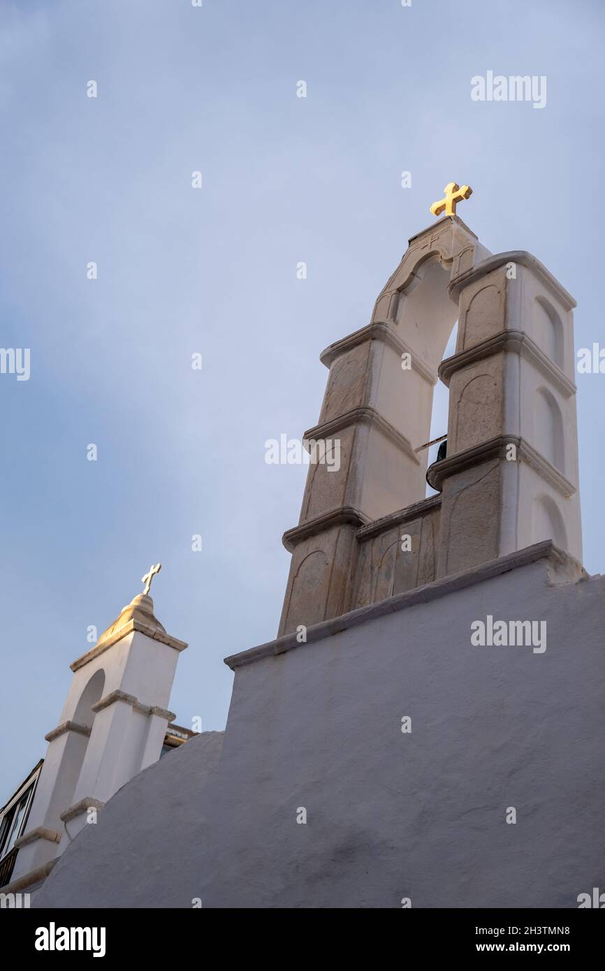 Kykladen Griechenland. Weiße orthodoxe Kirche zwei Glockentürme mit goldenem Kreuz. Weiß getünchte Wand vor blauem Himmel Hintergrund. Mykonos Island, Stockfoto