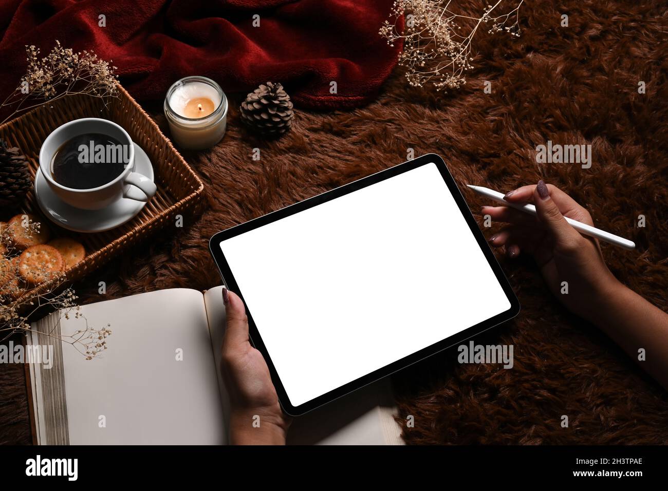 Frau mit Stylus Pen und digitalem Tablet auf braunem Teppich. Stockfoto