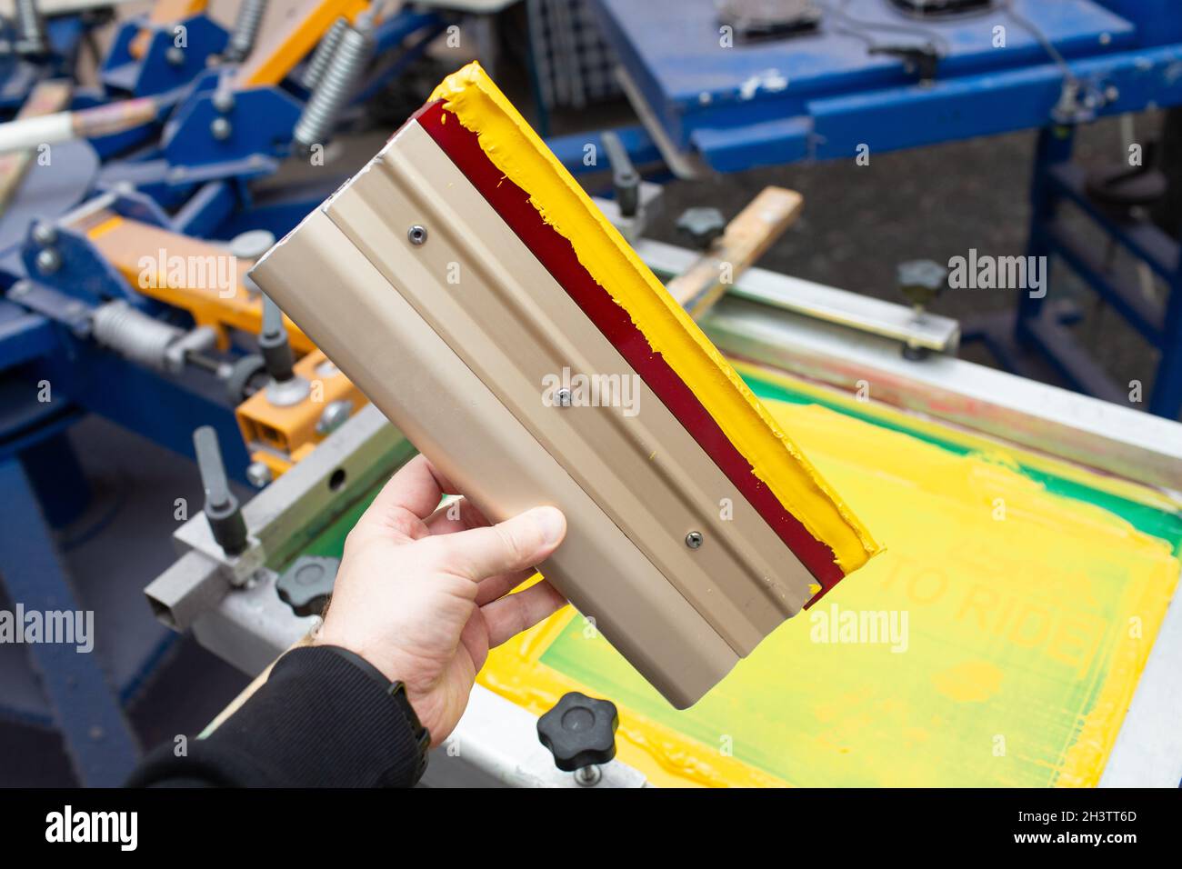 Rakel für Siebdruck-Siebdruck-Siebdruck in der Bekleidungsfabrik. Rahmen-, Rakel- und Plastisolfarben Stockfoto