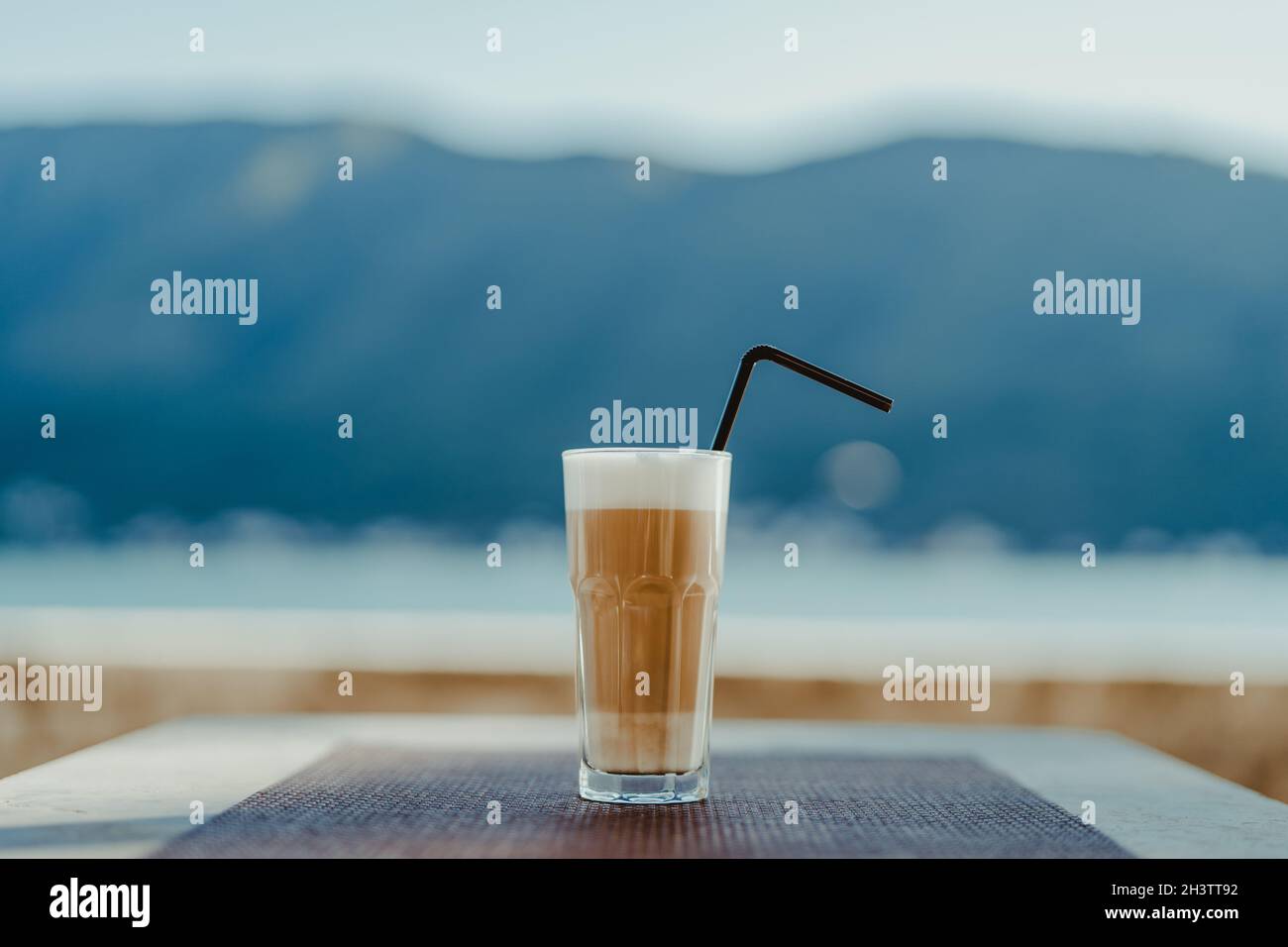 Facettiertes Glas mit Kaffee Latte und Stroh. Stockfoto