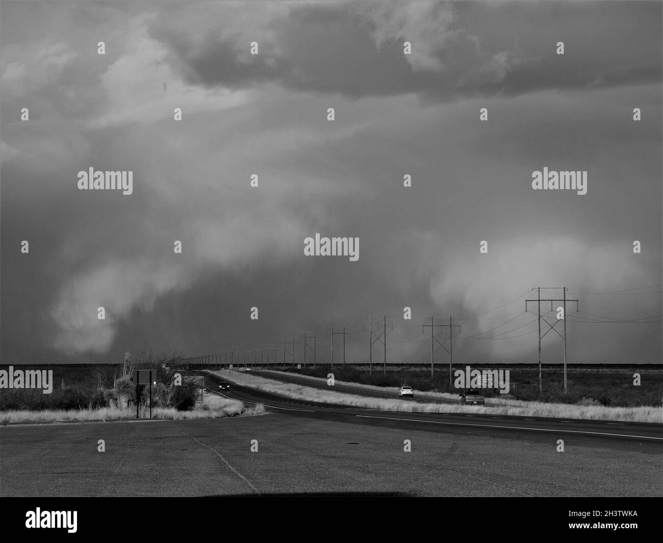 Schwarz-weiße Landschaften entlang der US 70 in New Mexico. Bedrohliche Wolken verdunkeln den fernen Horizont auf einer leicht befahrenen Landstraße. Stockfoto