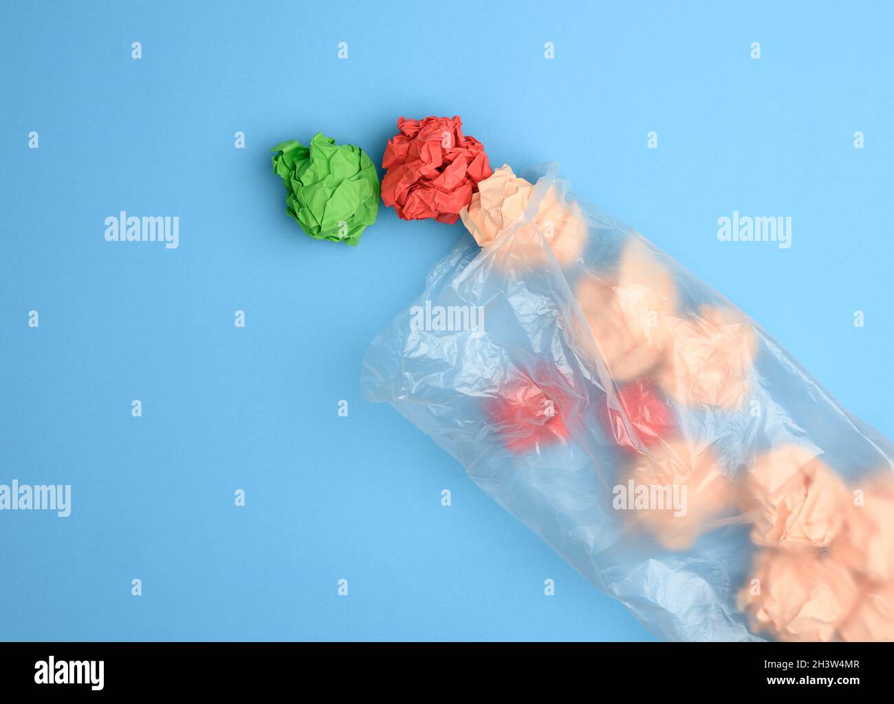 Transparente Plastiktüte mit zerknittertem Papier auf blauem Hintergrund Stockfoto