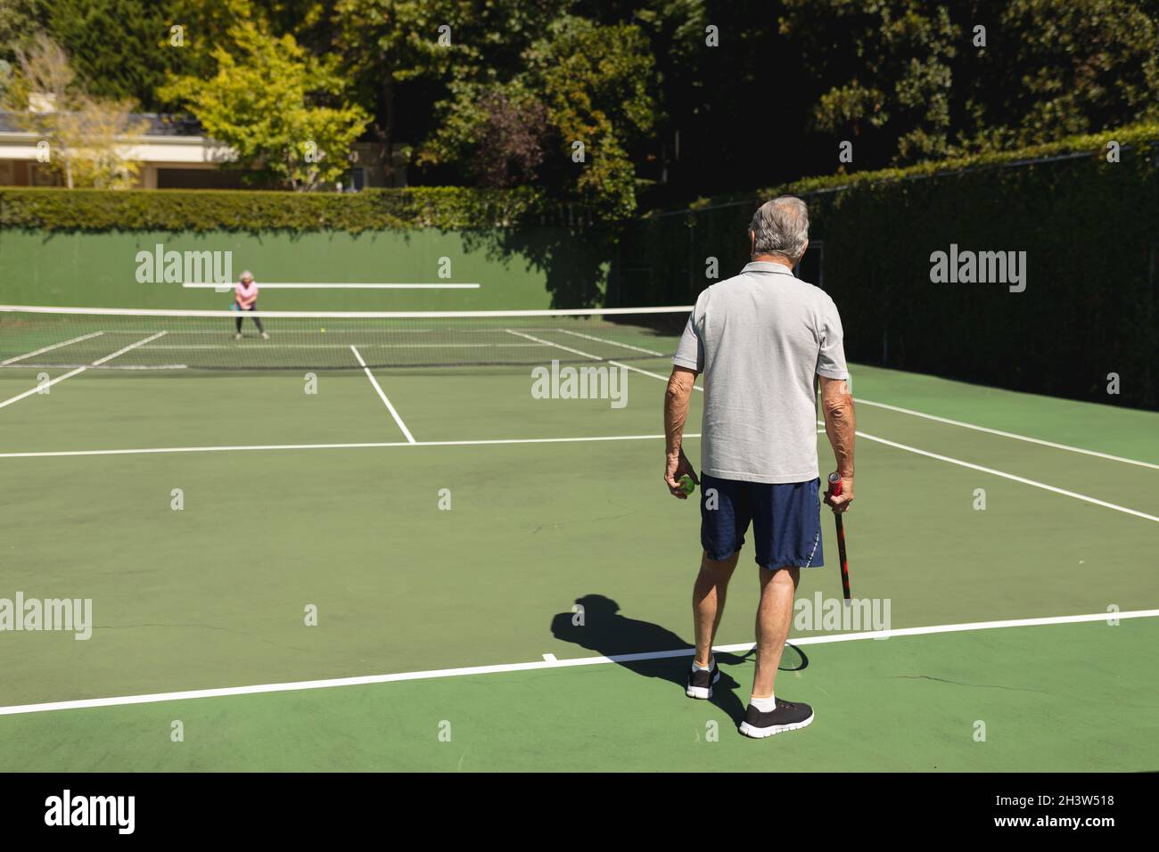 Ältere kaukasische Paare spielen gemeinsam Tennis auf dem Platz Stockfoto