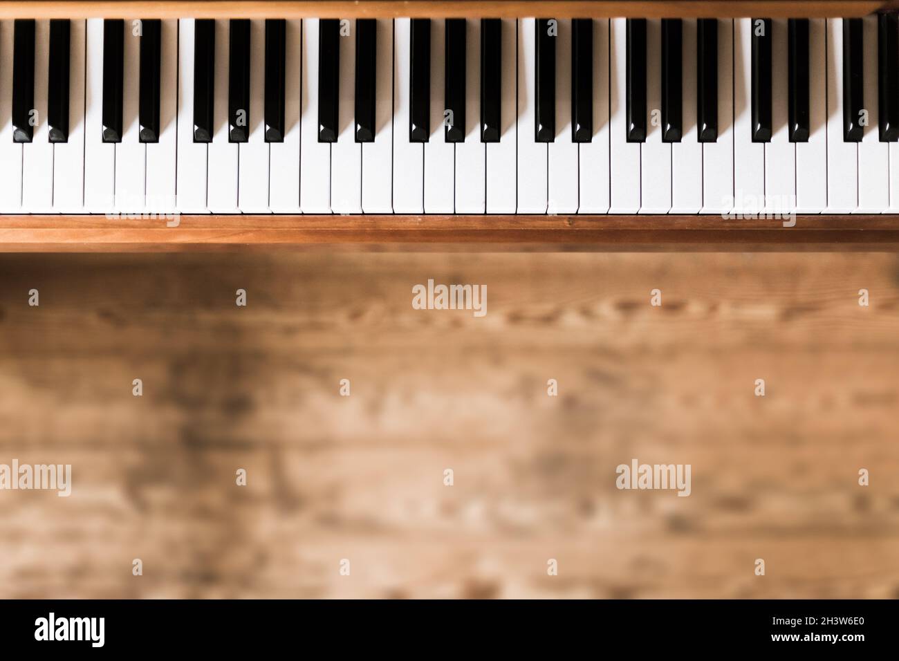 Klassisches Holzklavier. Tasten im Vordergrund, Holzboden mit Textzeilen im verschwommenen Hintergrund Stockfoto