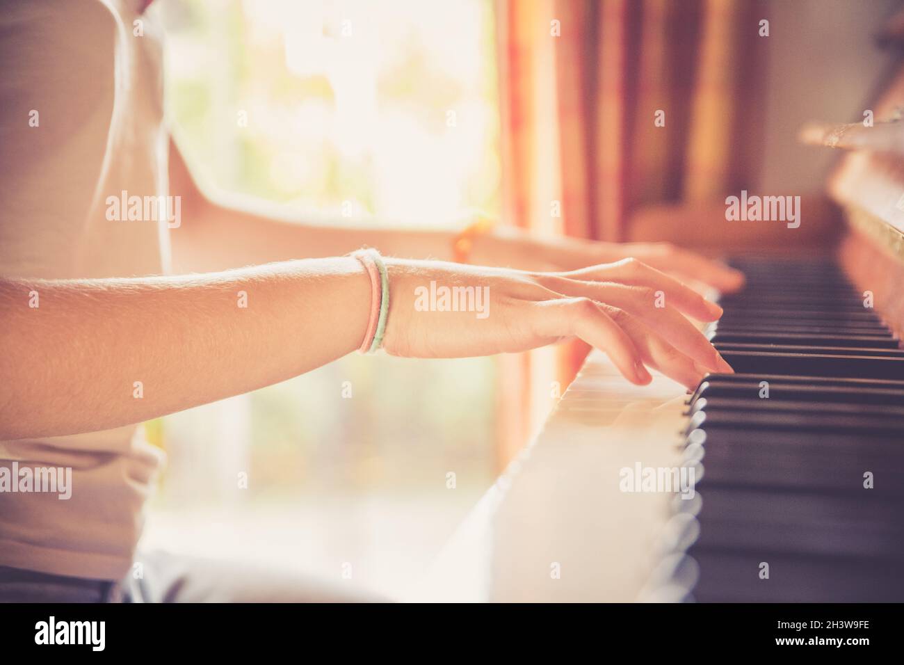 Mädchen spielt Klavier zu Hause, High-Angle-Ansicht, verschwommener Hintergrund. Stockfoto
