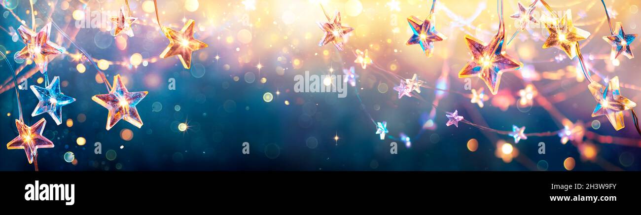 Weihnachtssterne Mit Goldenen Lichtern Auf Blauem Hintergrund - String Mit Abstraktem, Unfokussiertes Bokeh Stockfoto