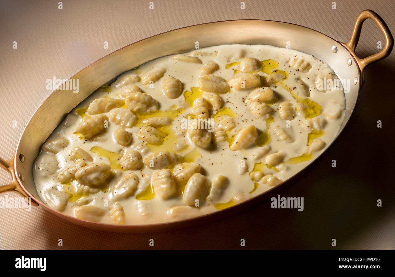 Italienische Gnocchi mit Käsesauce castelmagno-Käsesauce in einem ovalen Kupfertopf Stockfoto