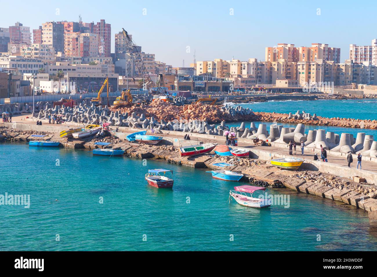Alexandria, Ägypten - 14. Dezember 2018: Blick auf die Küstenstadt mit Fischerbooten. Fischer sind auf Beton Wellenbrecher im Hafen von Alexandria Stockfoto