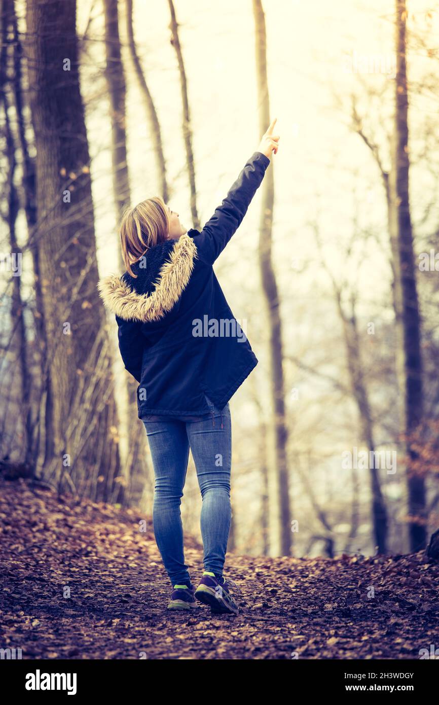 Niedliches junges Mädchen mit blauem parker steht im Herbst im Wald Stockfoto