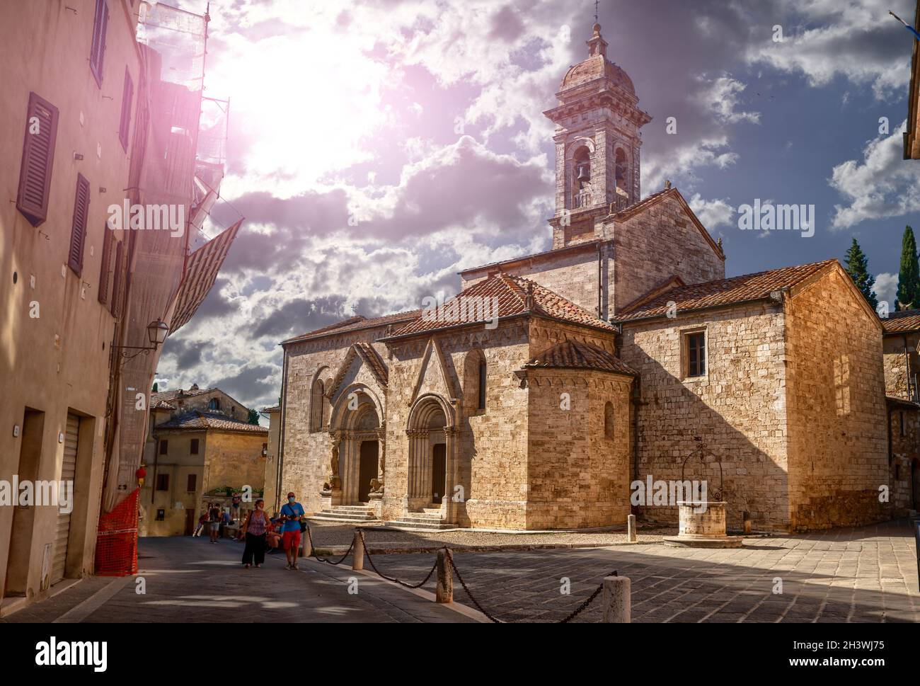 San Quirico d'Orcia, Toskana, Italien. August 2020. Die Stiftskirche von San Quirico d'Orcia. Im Hintergrund Touristen mit Coronavirus-Masken. Stockfoto