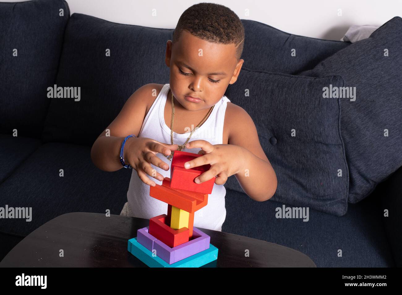 Vorschulkind zu Hause, spielen mit bunten Holzblöcke Puzzle, balancieren auf Block auf der Oberseite der Konstruktion Stockfoto