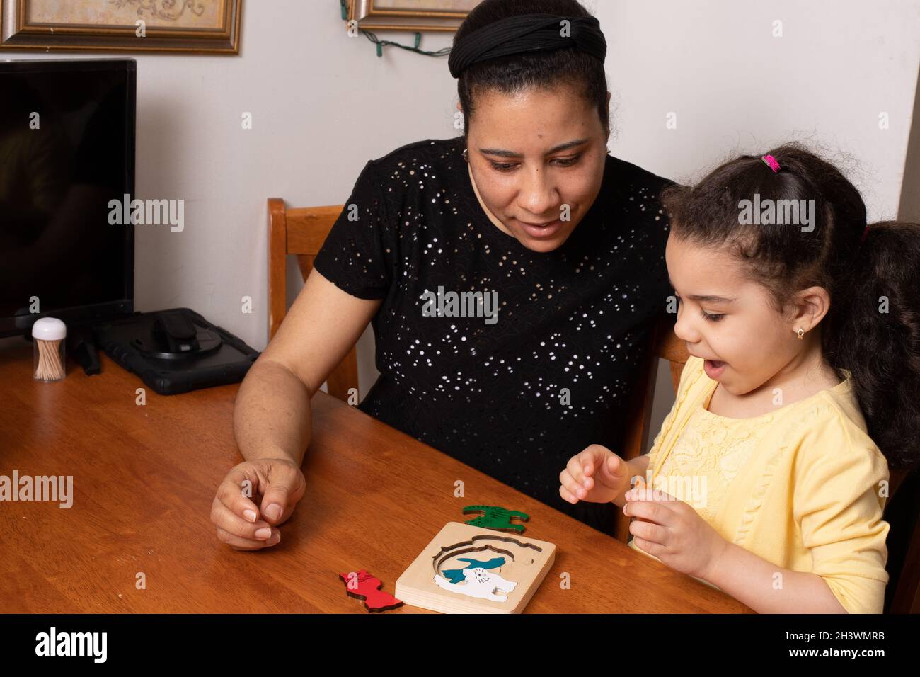 Vorschulkind, 4 Jahre alt, zu Hause mit Mutter, die mit neuen Holzpuzzles spielt, begeistert und interessiert an Aktivität Stockfoto