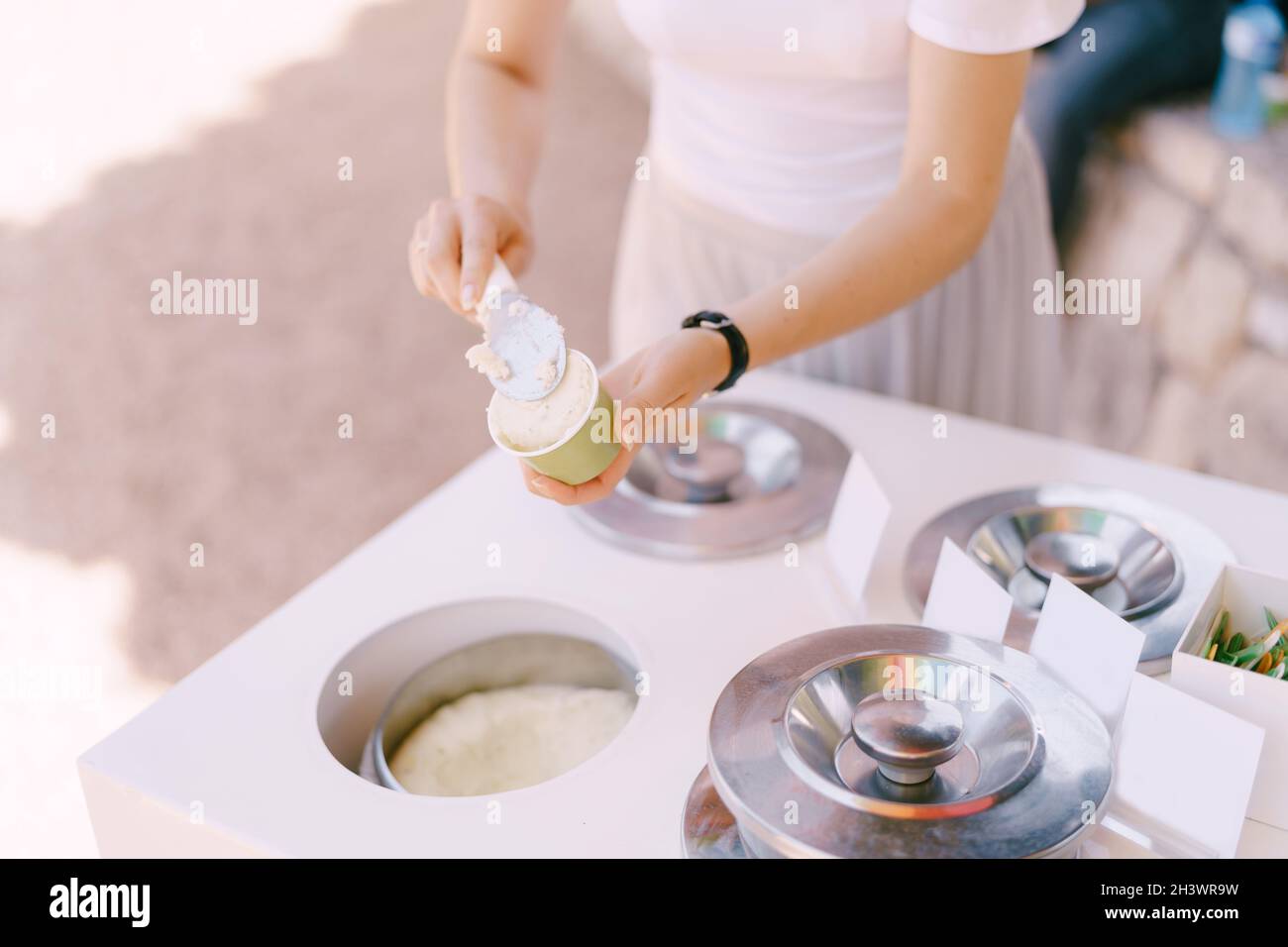 Eisverkäufer legt das Eis in die Tasse. Stockfoto