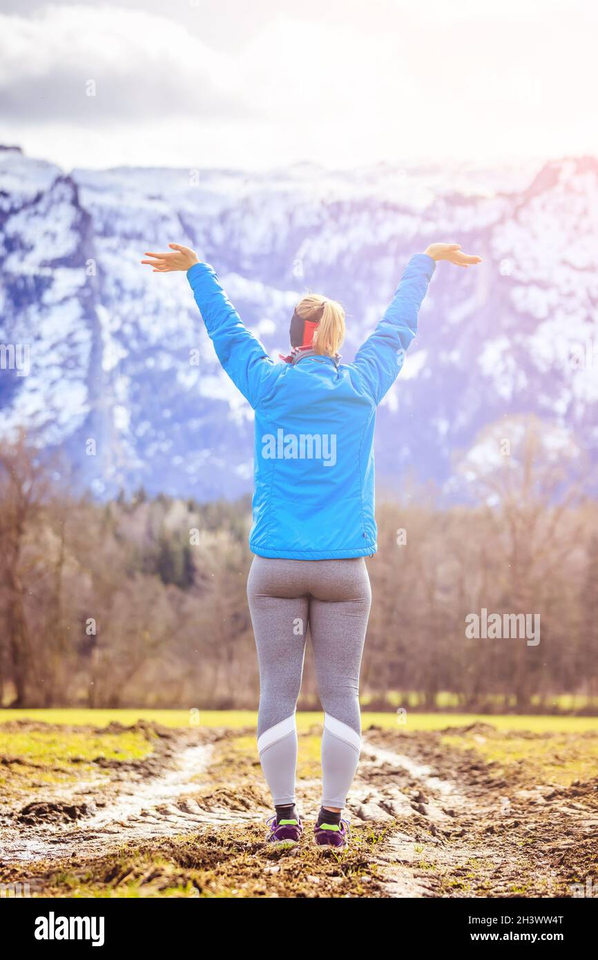 Junge Frau in Sportkleidung steht auf einem Feld, wunderbar-Geste Stockfoto